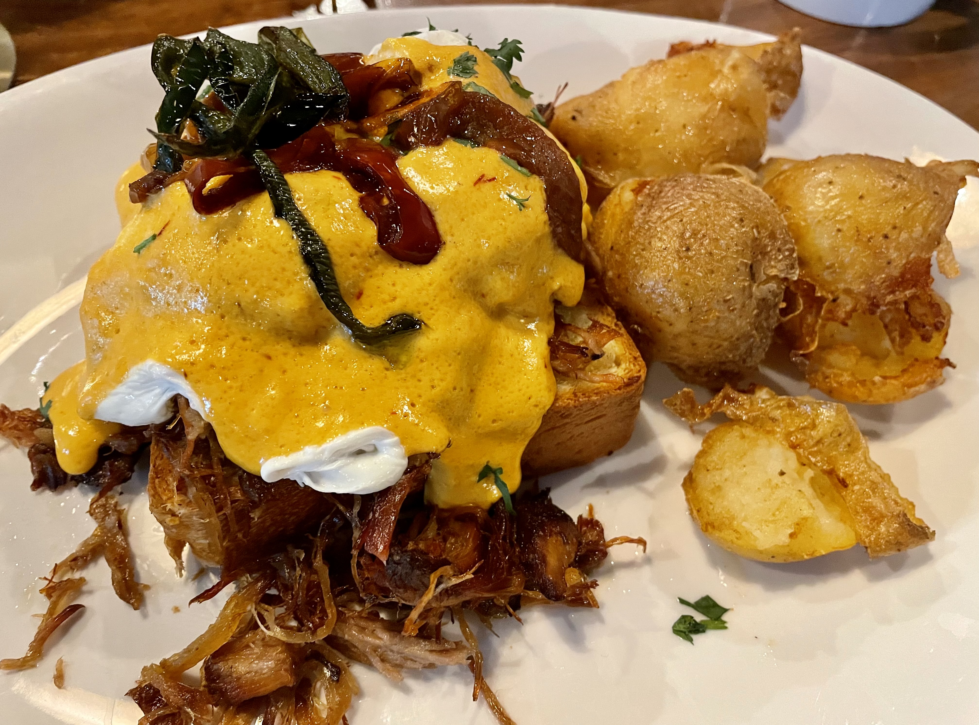 Tucson food. Carnitas Benedict. gs on top of orange and cinnamon braised pork, smothered in chipotle hollandaise, with potatoes on the side.