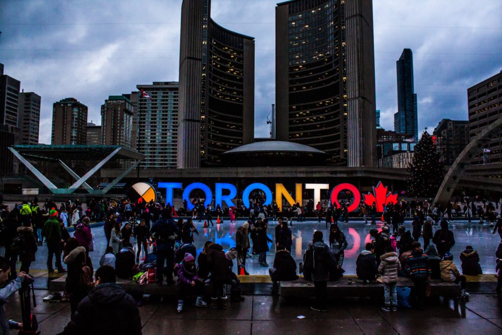 Toronto, Canada as sun goes down with people ice skating in front of Toronto lit sign in the city