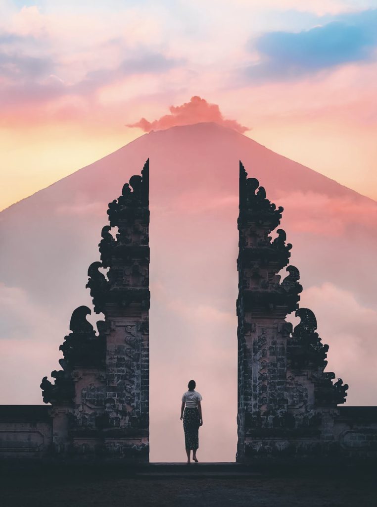 Woman standing in Canggu, Indonesia with pink skies in the background