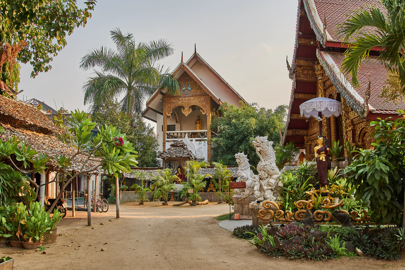 Temples in Chiang Mai, Thailand with two story buildings, dragons and palm trees with green foliage